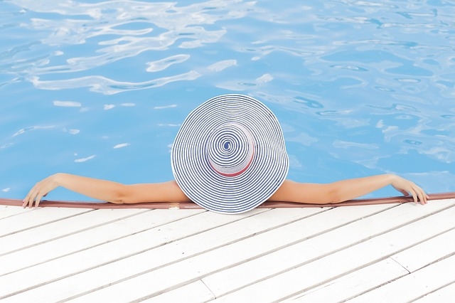 woman in pool with large sun hat