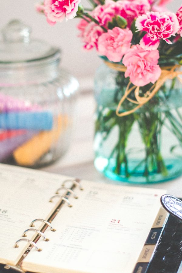 calendar planner on desk with flower arrangement